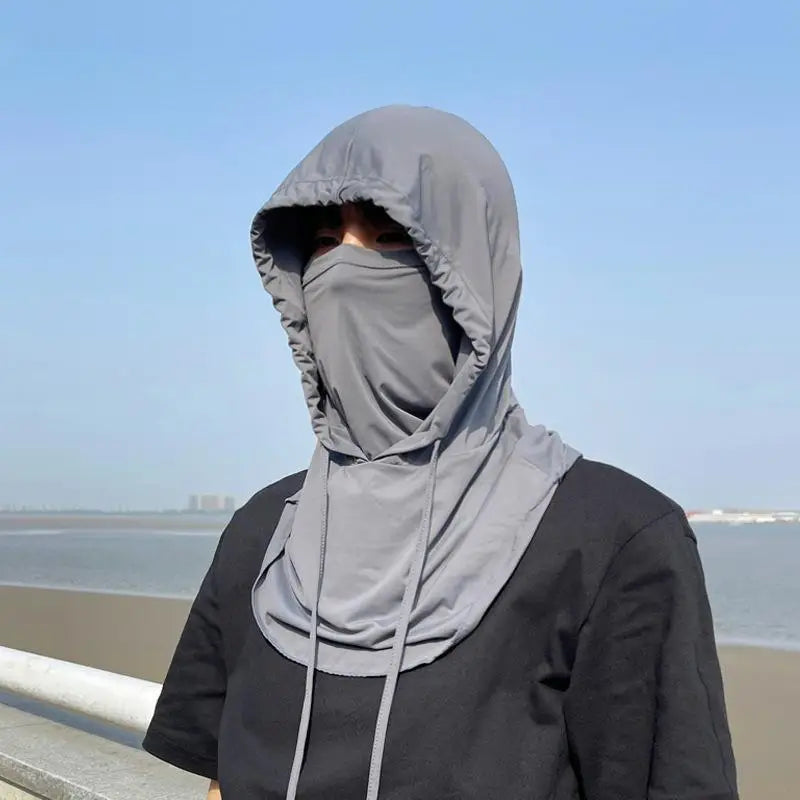 A person wearing a gray breathable UV protection balaclava face mask and long neck cover outdoors.