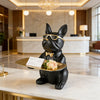 A black decorative bulldog statue wearing gold-rimmed glasses sitting on a gold tray.
