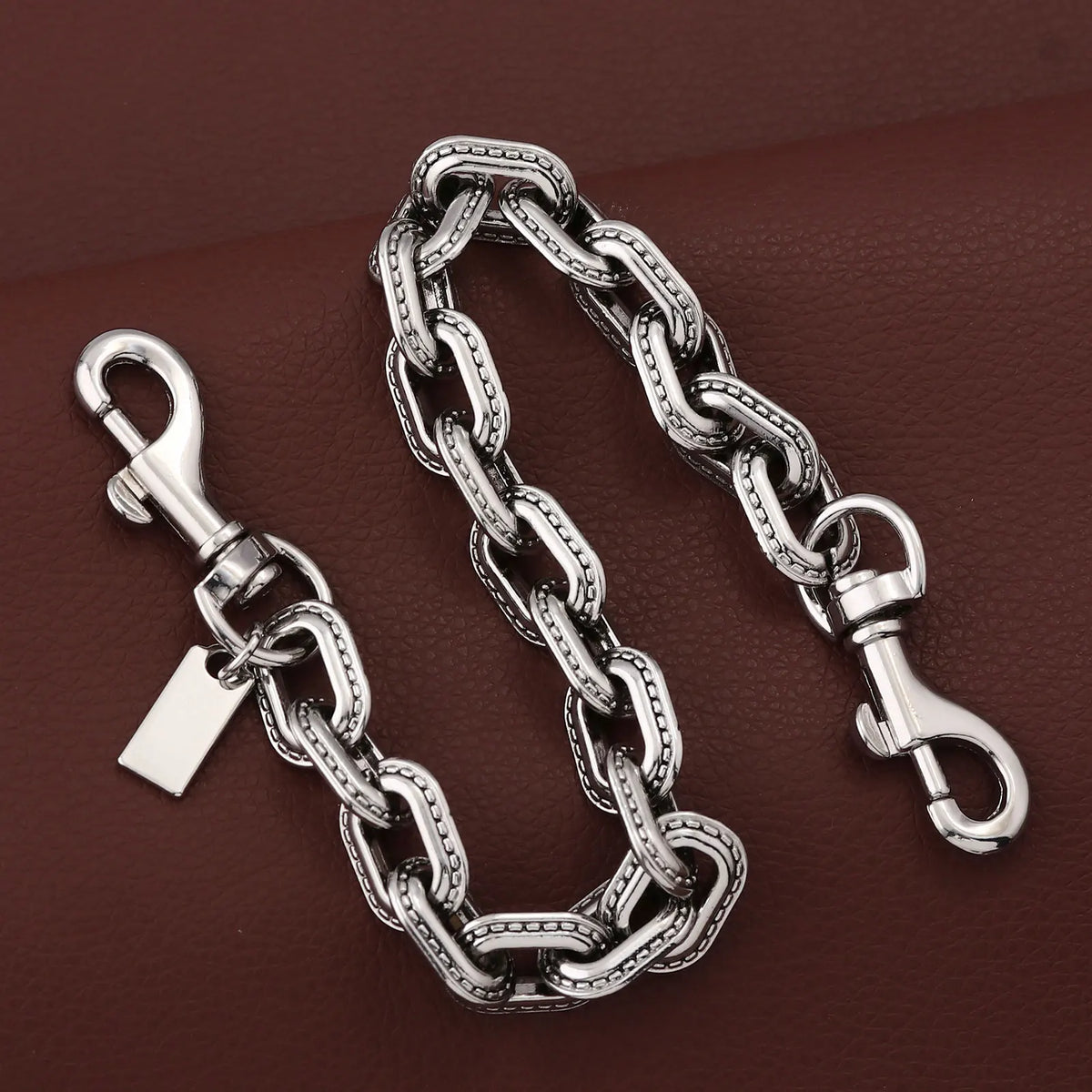 A silver and white gold two-tone metal chain necklace with a pendant resting on a dark brown surface.