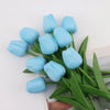 A bouquet of light blue artificial tulips with green stems and leaves.