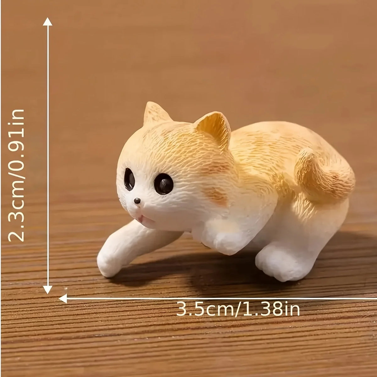 A small, light orange and white cat figurine is shown lying down on a wooden surface.