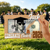 A wooden sign featuring a portrait of Jack surrounded by US hundred dollar bills and the text Congrats Class of 2026