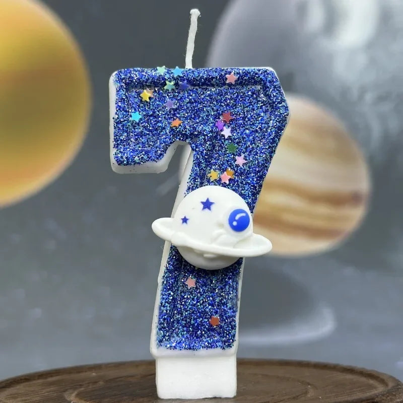 A birthday candle shaped like the number 7 decorated with blue glitter and a white planet design