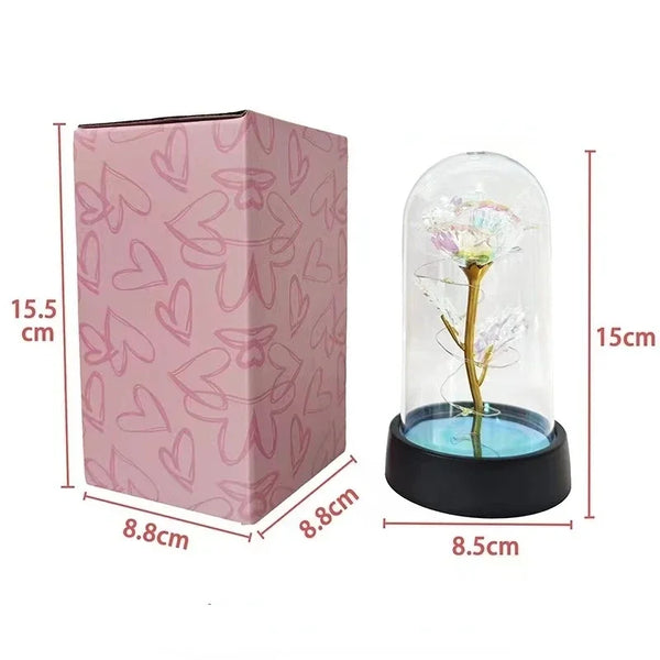 A pink cardboard box containing an eternal rose LED night light with a warm glow and a glass enclosure.