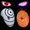 A white ninja mask with black markings and glowing purple eyes, next to an orange swirling mask.