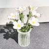 A bouquet of white and yellow flowers in a clear glass vase