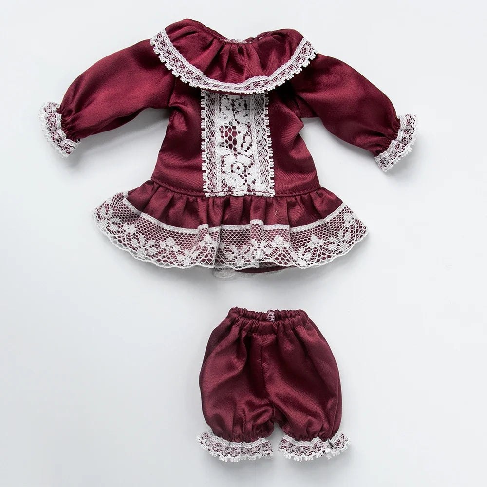 A vintage lace pajama set for a doll featuring a maroon top and matching bottoms with white lace trim.