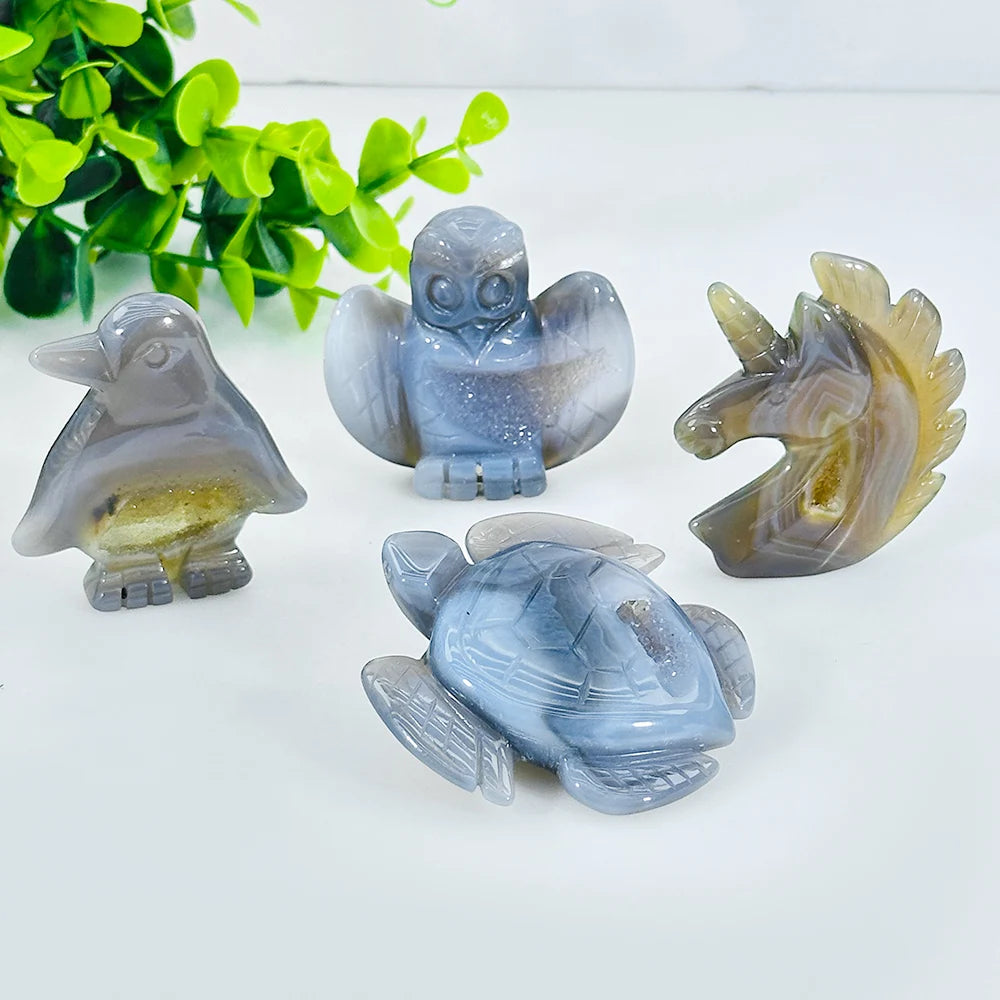 A set of natural agate crystal figurines depicting a bird, a owl, and a turtle on a white background.