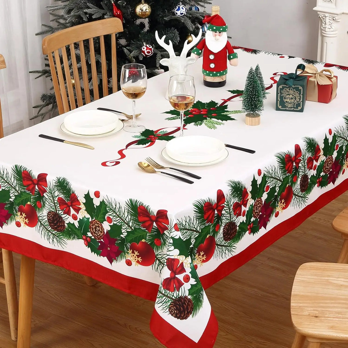 A festive Christmas poinsettia rectangle tablecloth set for a dining table decorated with greenery and gifts.