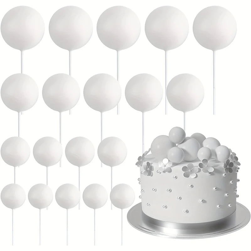 A set of twenty white spherical cake toppers on sticks arranged above a silver cake plate.