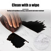 A hand wipes a black, oil-repellent surface onto a marble countertop.
