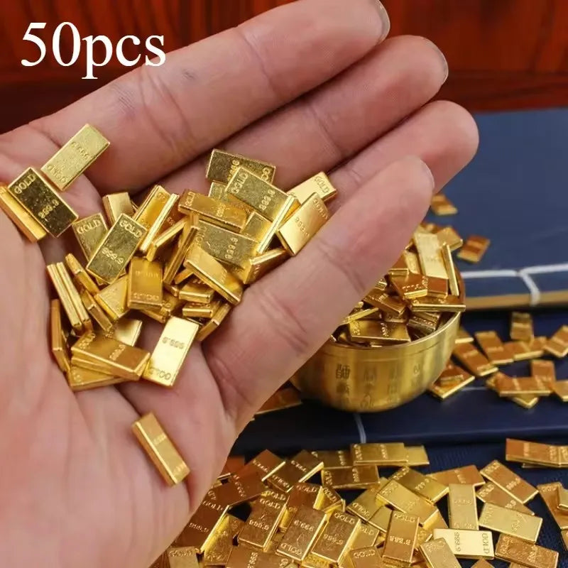 A hand holds a pile of small, rectangular gold-colored bars for customizable simulated gold bar decor.