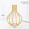 Gold bottle-shaped wire vase with a clear glass body and thin metal wires for flower arrangements