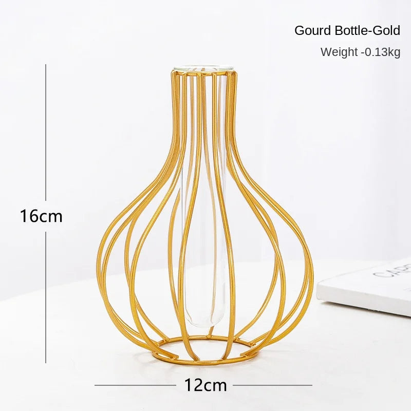 Gold bottle-shaped wire vase with a clear glass body and thin metal wires for flower arrangements