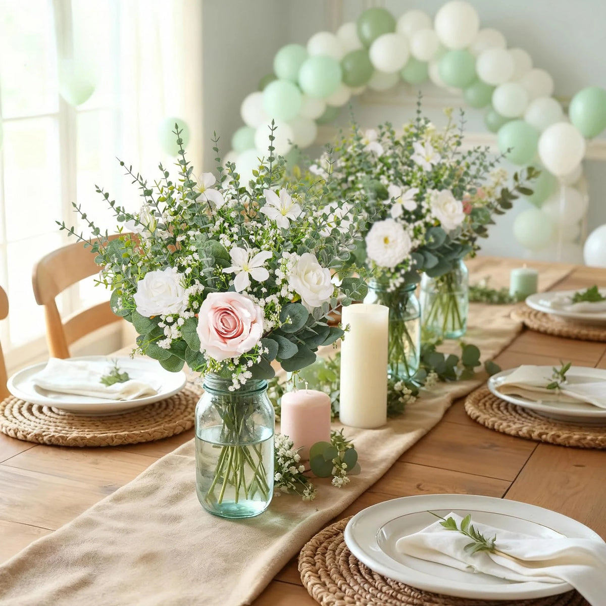 Una mesa rústica con arreglos florales de rosas blancas y rosas y follaje, sobre un fondo claro
