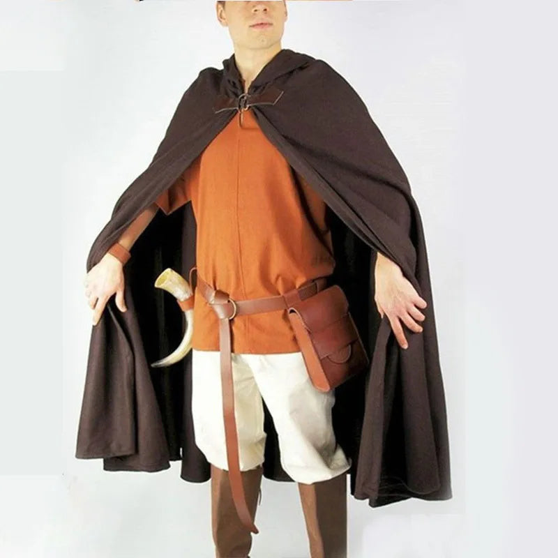 A person wearing an orange shirt and white pants is draped in a dark brown velvet hooded cloak.