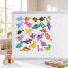 A collection of colorful dinosaur fridge magnets displayed on a white board next to wooden blocks.