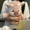 Une personne tient un jouet en peluche Kawaii Highland Calf rose devant un ordinateur portable.