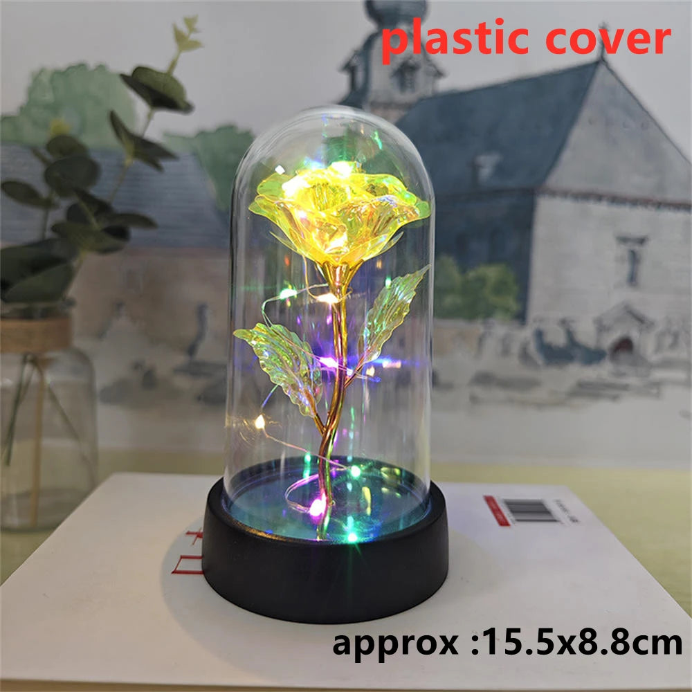 An LED galaxy rose artificial flower displayed inside a glass dome on a black base.