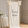 A cream linen banner with gold trim and bow ties displayed against a light wall.