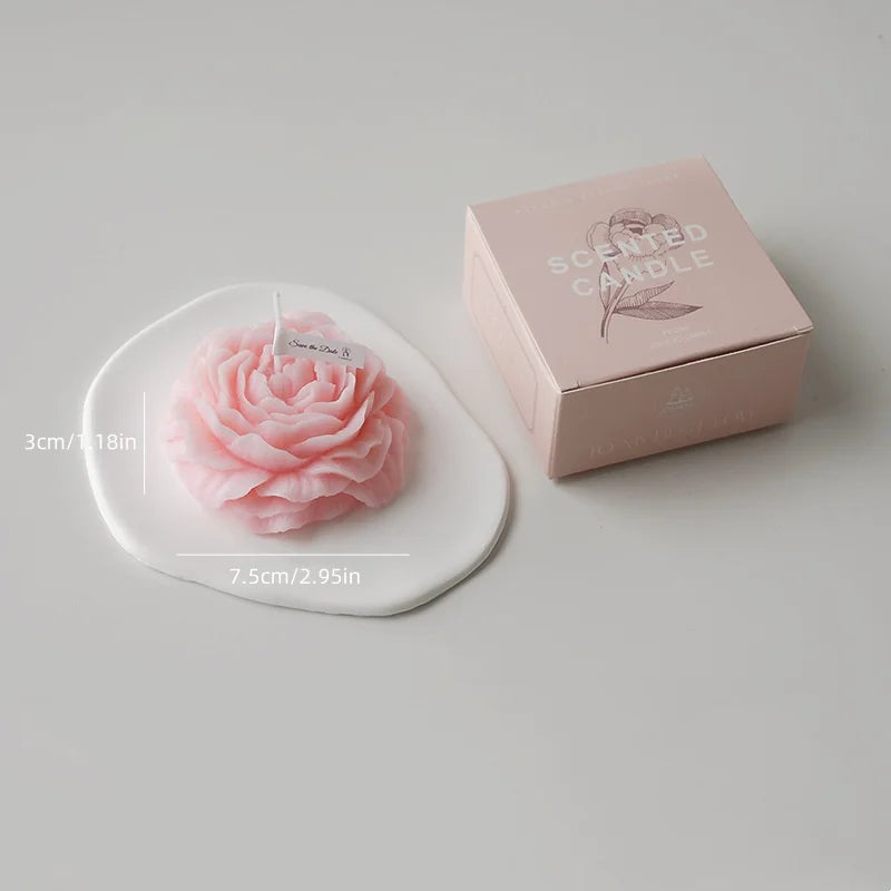 A pink rose-shaped scented candle is displayed next to its rectangular box.