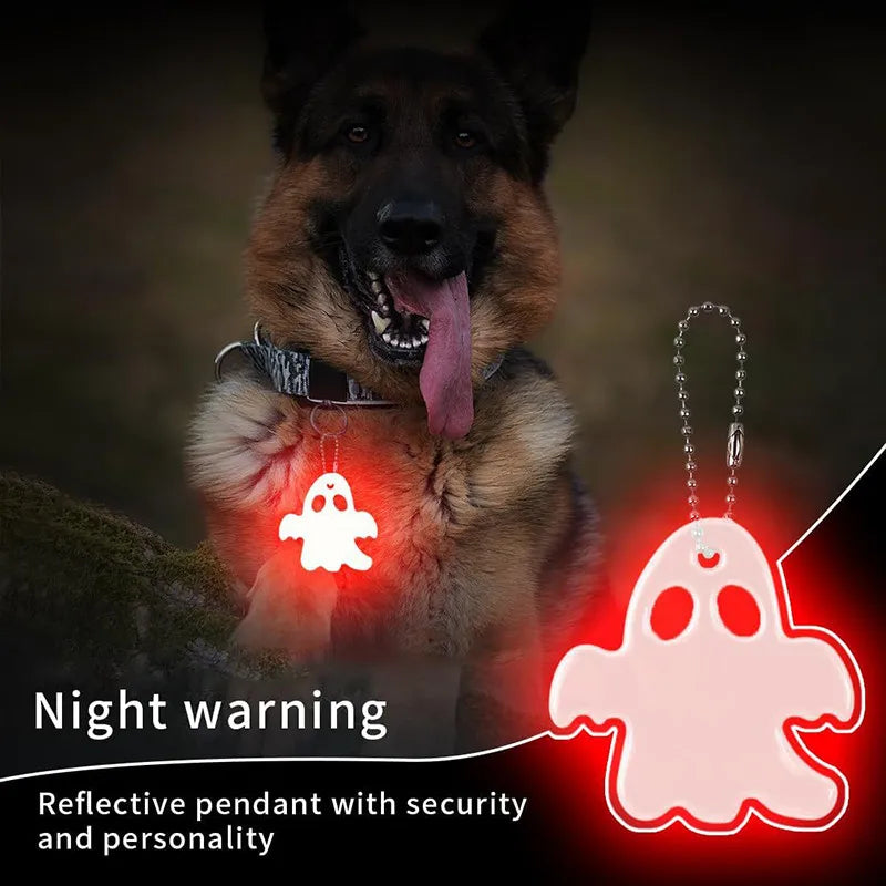 A German Shepherd dog wearing a reflective pendant shaped like a ghost against a dark background.