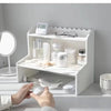 A white two-layer desktop organizer shelf displaying neatly stored items like glasses and skincare products.