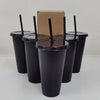 A set of black reusable tumblers with lids and straws are displayed next to a cardboard box.