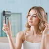 A woman is using a portable handheld fan with a silver finish to cool her face.