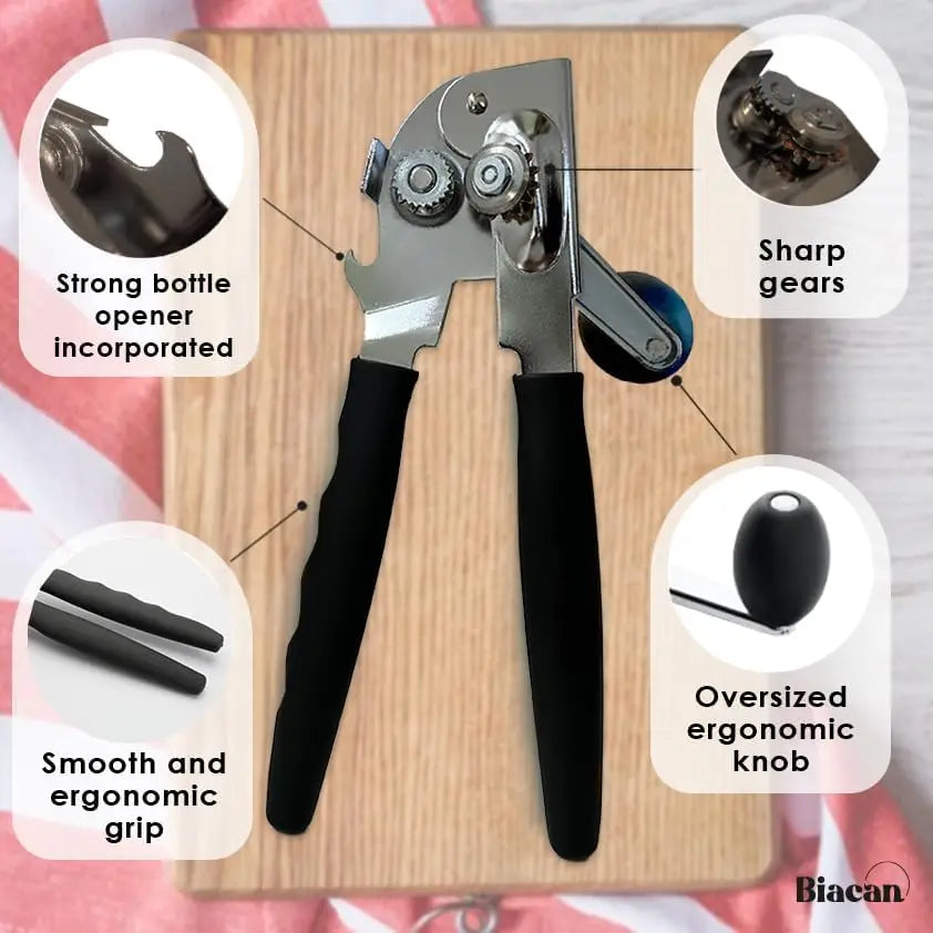A black heavy-duty manual can opener with a smooth grip and sharp gears resting on a wooden board.