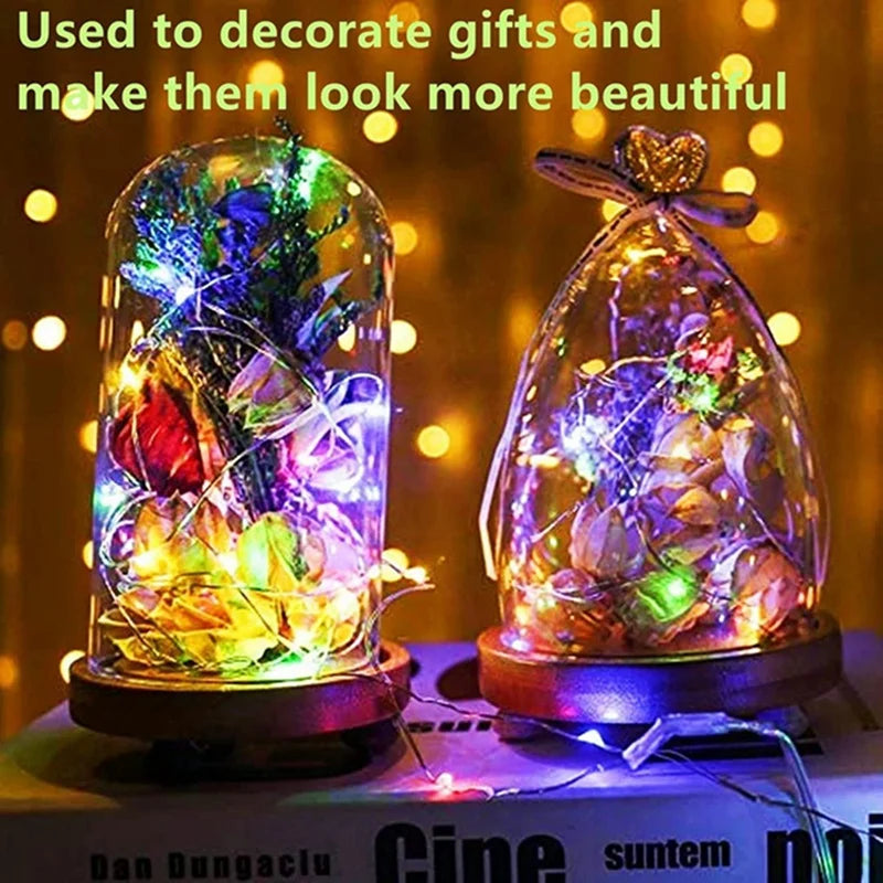 Two glass decorative lanterns illuminated by fairy lights, used to decorate gifts.