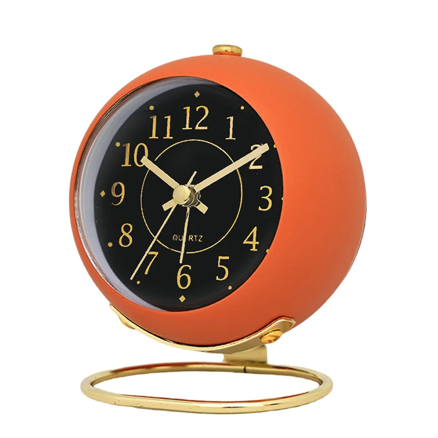 A minimalist Nordic alarm clock with an orange spherical face and gold accents.