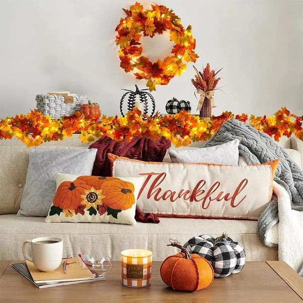 An autumn maple leaf artificial vine wreath decorated with orange and yellow leaves on a white background.