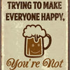 A vintage-style metal sign with text that reads Stop Trying to Make Everyone Happy, You're Not Beer, and a beer mug graphic.