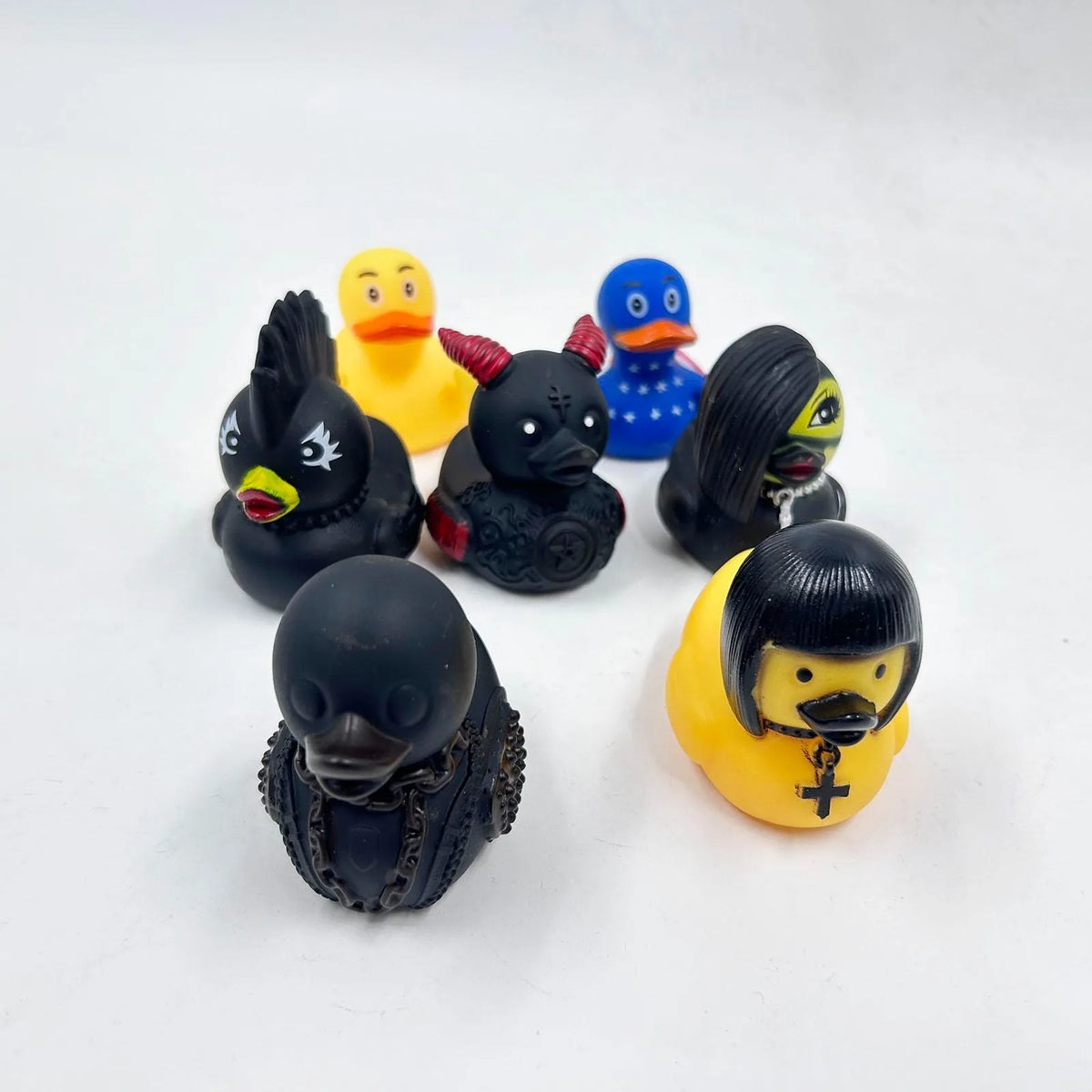 A set of seven black and yellow rubber duck figurines with various facial features and accessories.