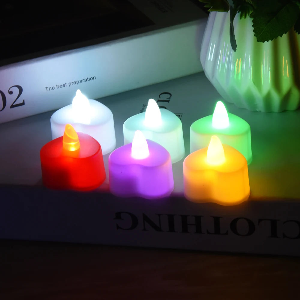 A collection of glowing LED heart-shaped tealight candles in various colors including white, green, purple, and orange.