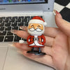 A hand holds a small clockwork wind-up figurine of a man with a white beard and a Santa hat.