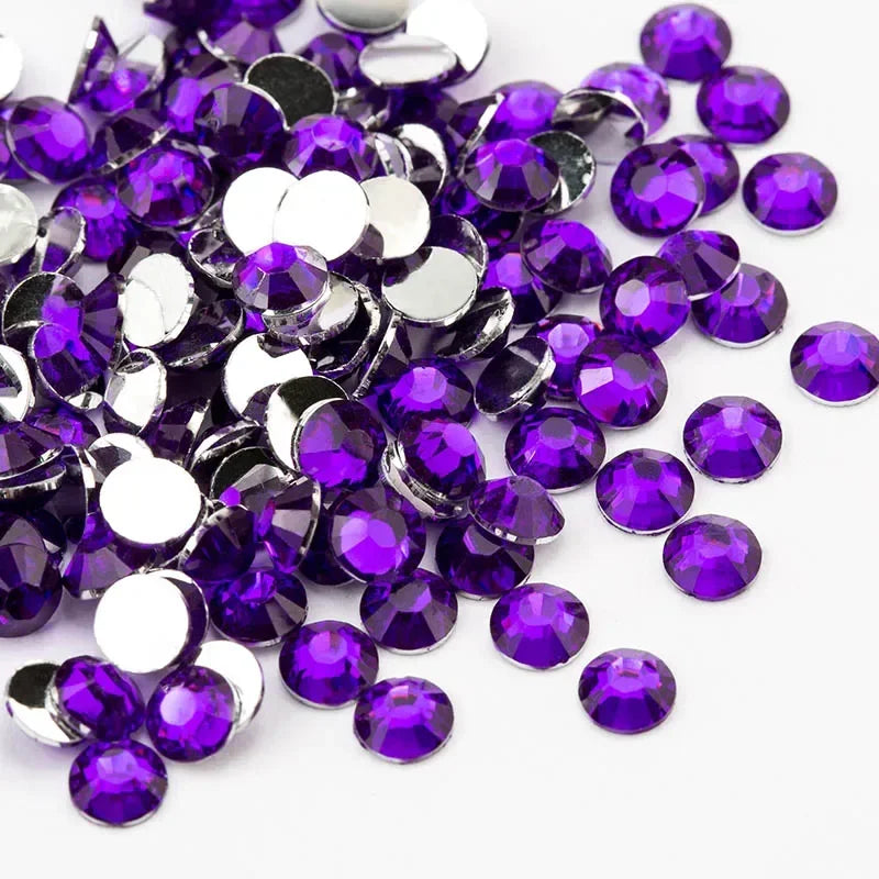 A pile of round flatback resin rhinestones in various shades of purple and silver.