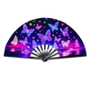 A folding rave hand fan with iridescent purple and blue fluorescent UV glow featuring butterfly and star patterns.