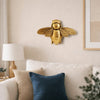 Handgefertigte goldene Bienenwandskulptur, montiert an einer hellbeigen Wand über einem weißen Sofa.