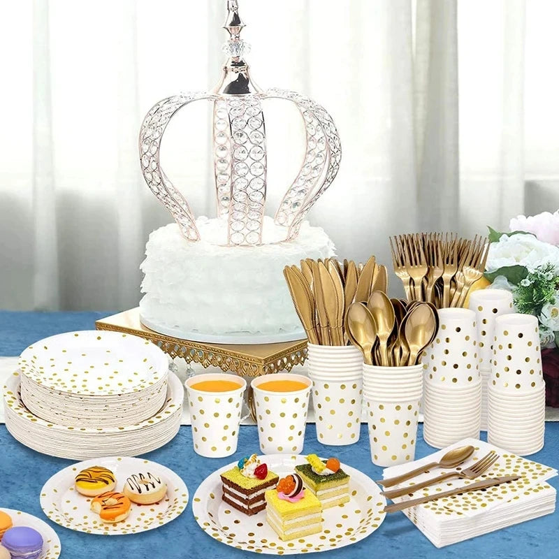 A display of gold polka dot disposable party tableware including plates, forks, and spoons on a blue cloth.