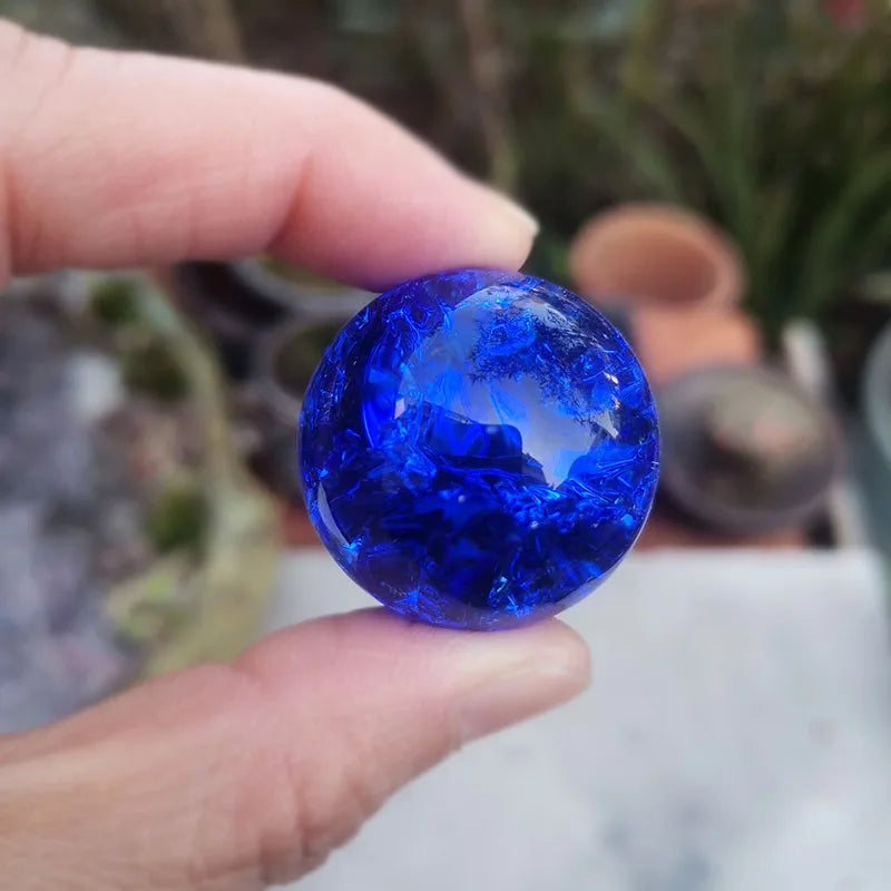 A hand holds a bright blue crystal ice crack ball used as water fountain decor.