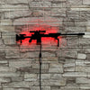 A red LED gun-shaped wall decor light is mounted on a gray stone wall.