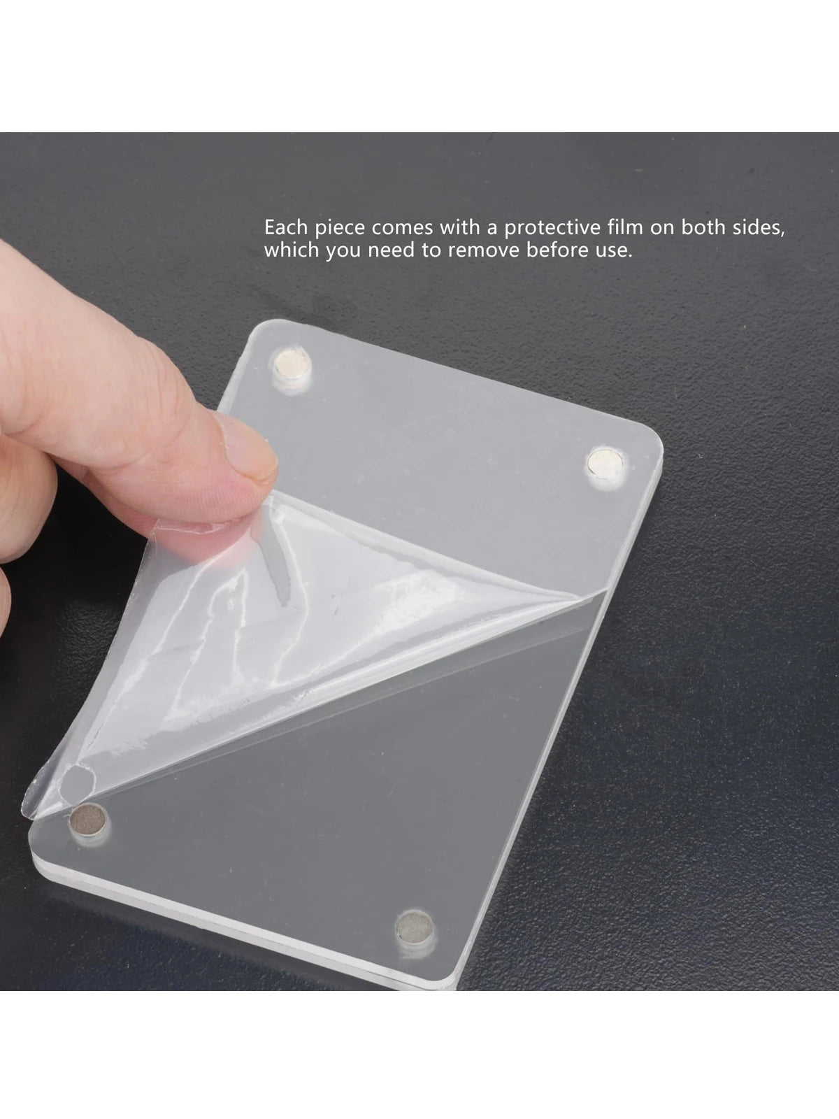 A hand is removing a protective film from a clear acrylic car sun visor photo clip piece.