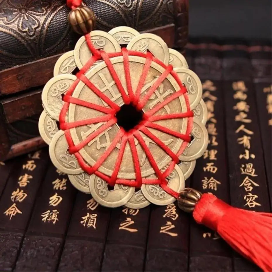 A round, layered knot wall decor made of light beige material with red string and a gold tassel, resting on dark wood.