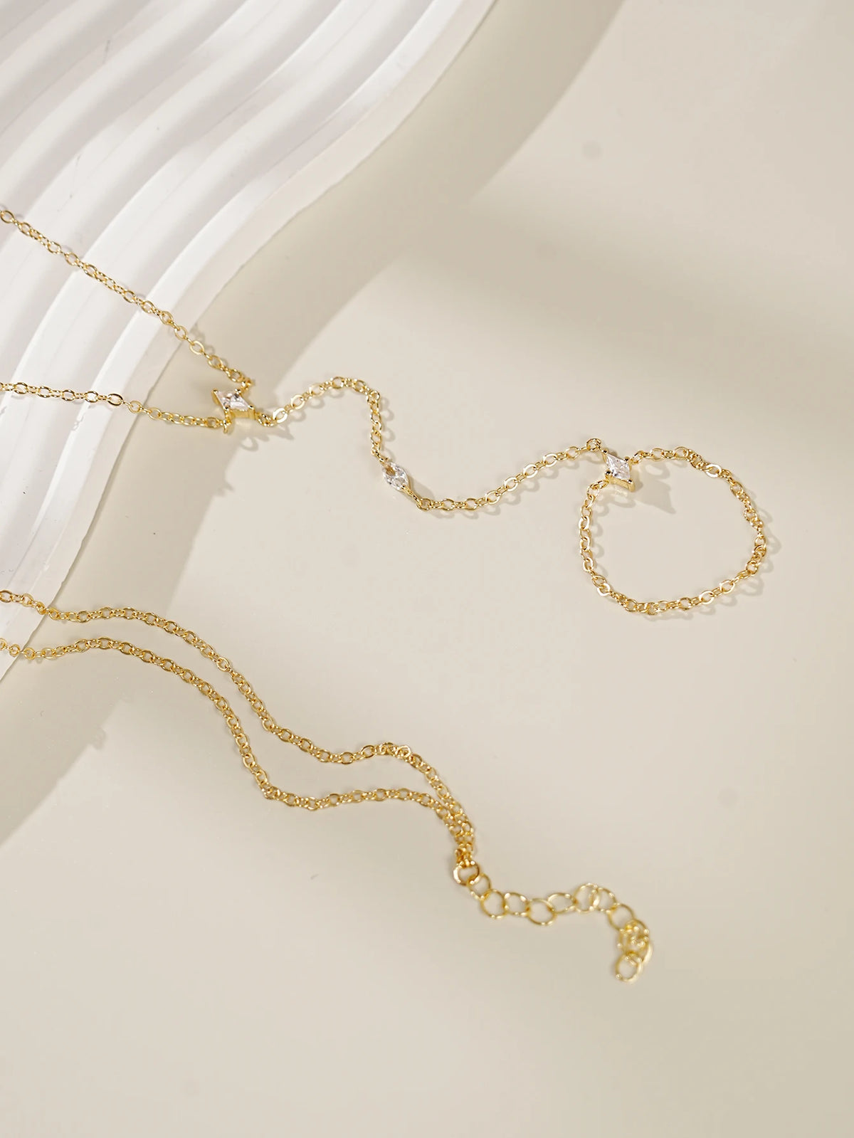 Gold ultra-thin layering chain bracelets with small clear stones displayed on a light background.
