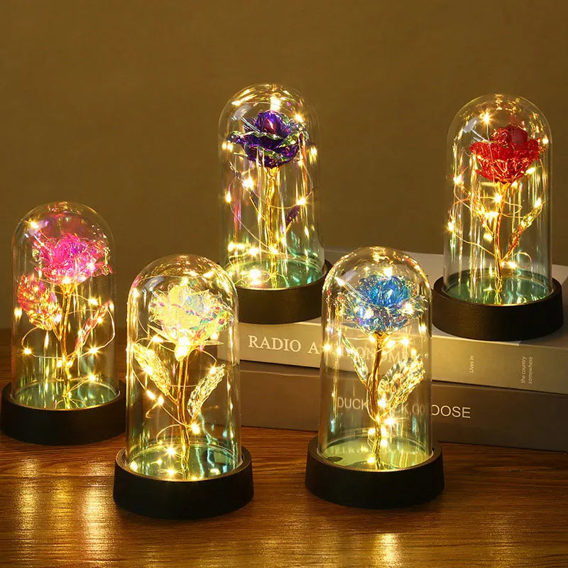 A collection of glass domes featuring preserved roses and glowing LED lights on a wooden surface.