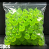 A clear plastic bag filled with numerous bright lime green glow-in-the-dark resin charms shaped like aliens and ducks.