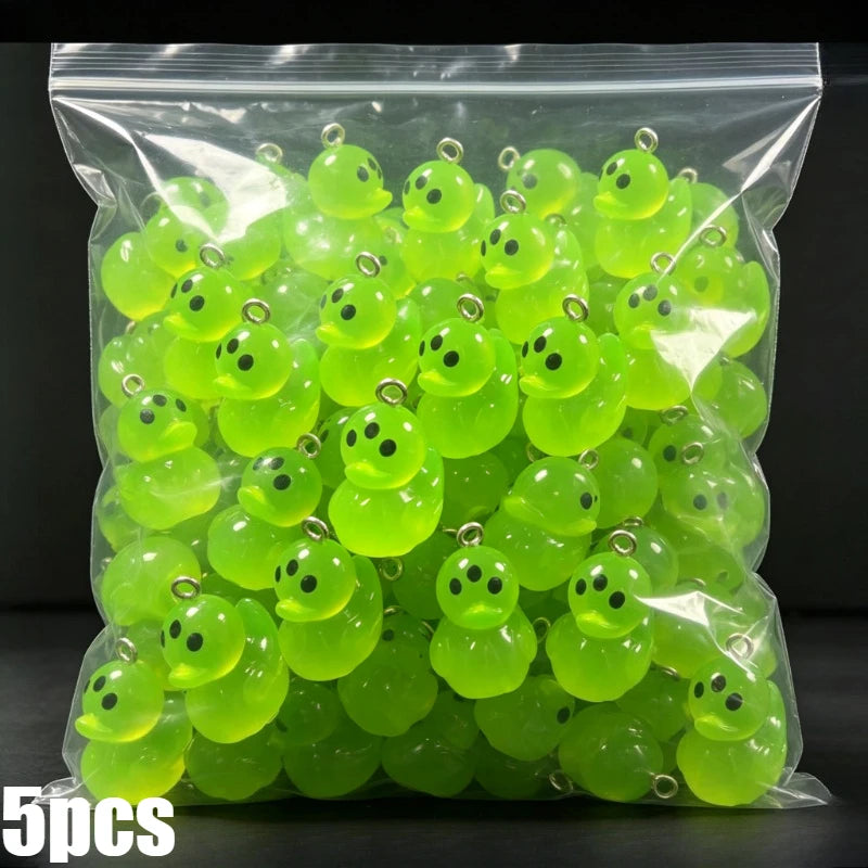 A clear plastic bag filled with numerous bright lime green glow-in-the-dark resin charms shaped like aliens and ducks.