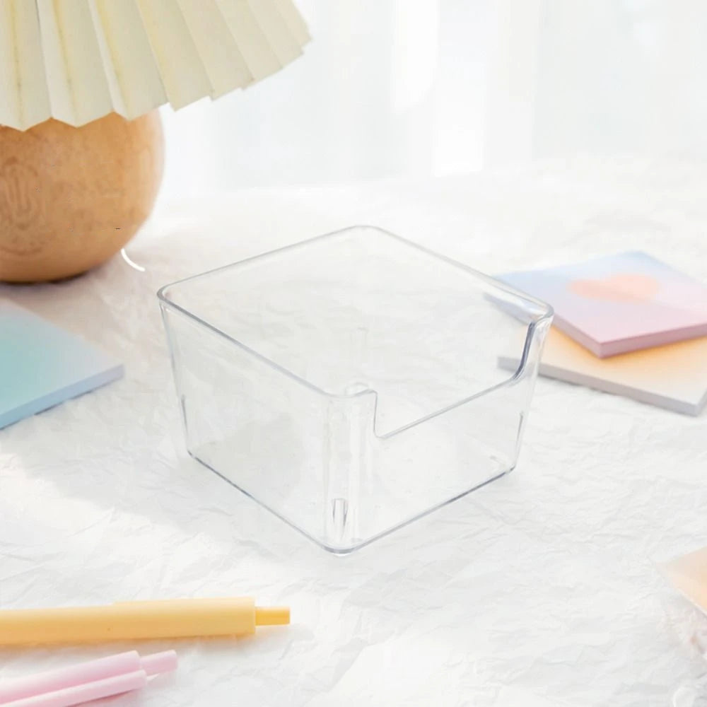 Une boîte de rangement pour bureau en acrylique transparent sur une surface blanche à côté d'un crayon jaune clair et de post